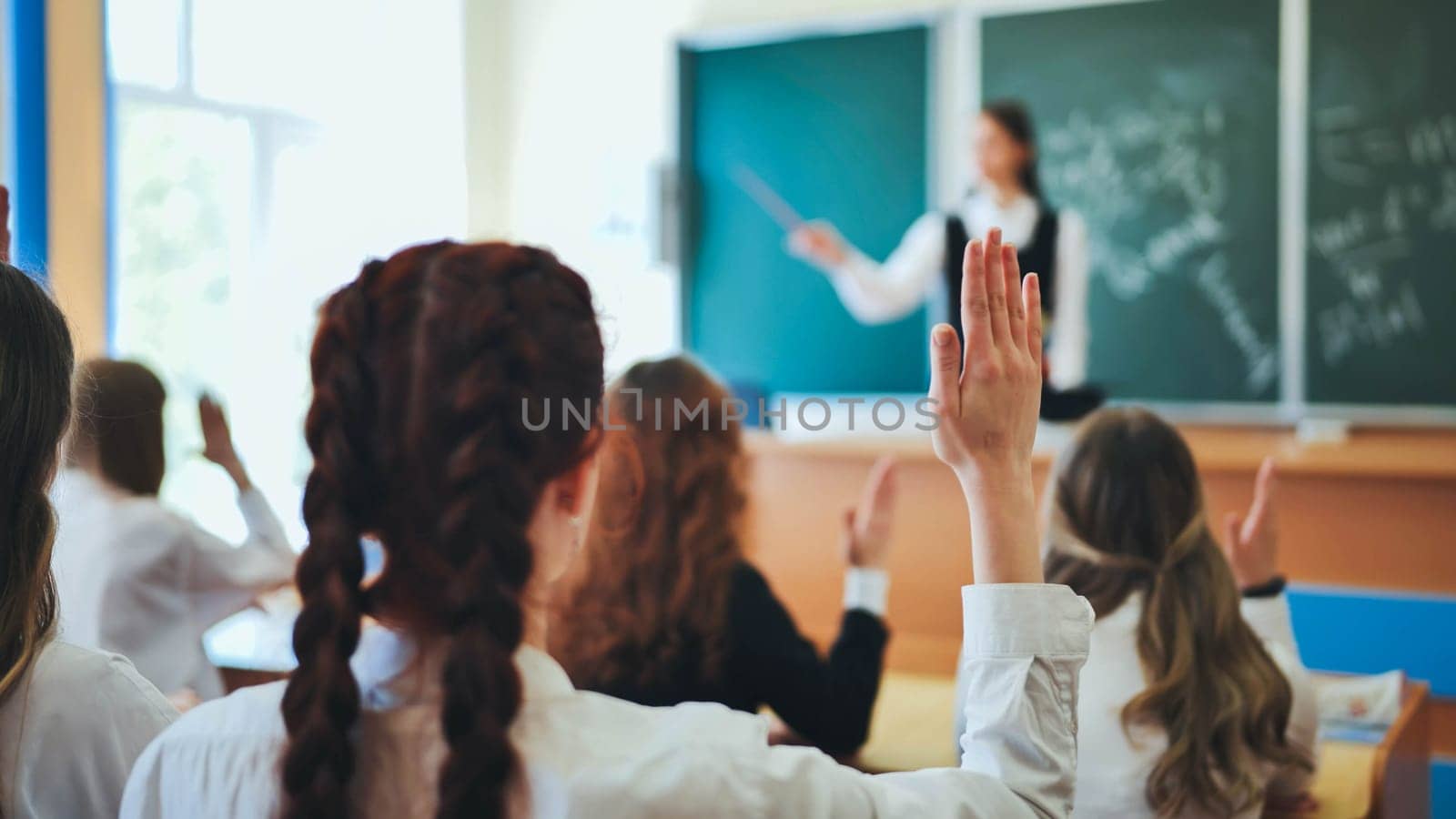 Girl students raise their hands in math class. by DovidPro