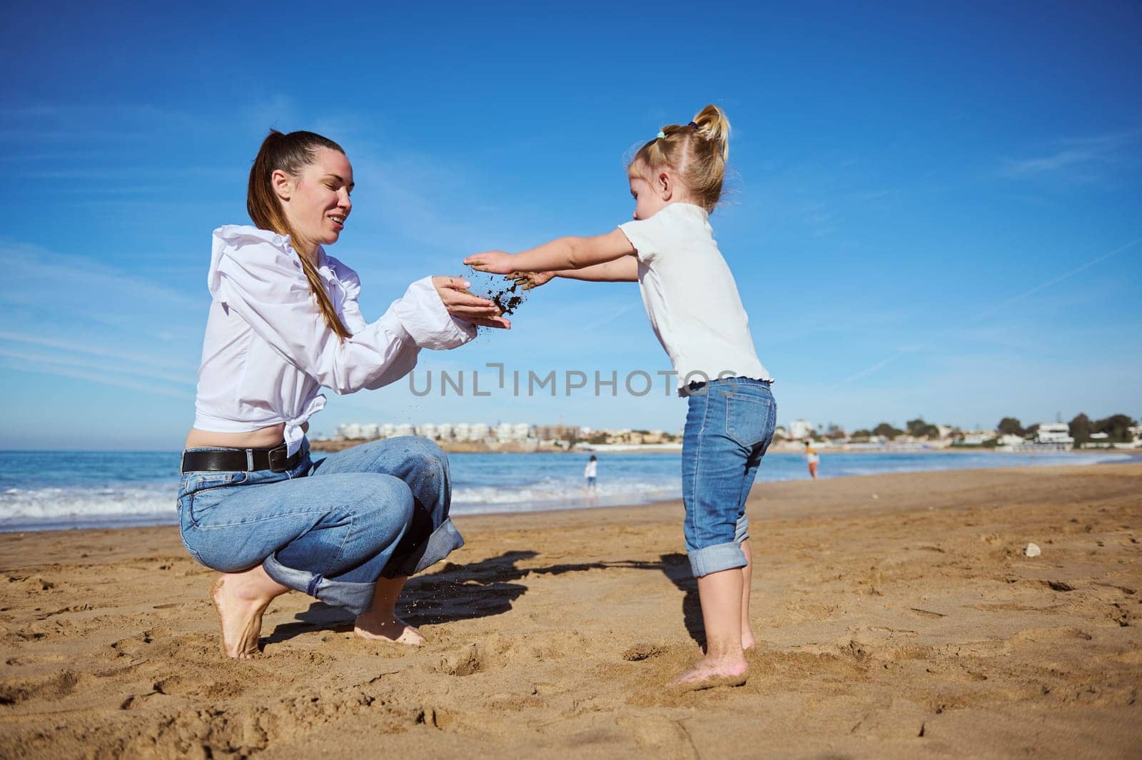 Mother and daughter playing on the beach together. Happy family relationships concept