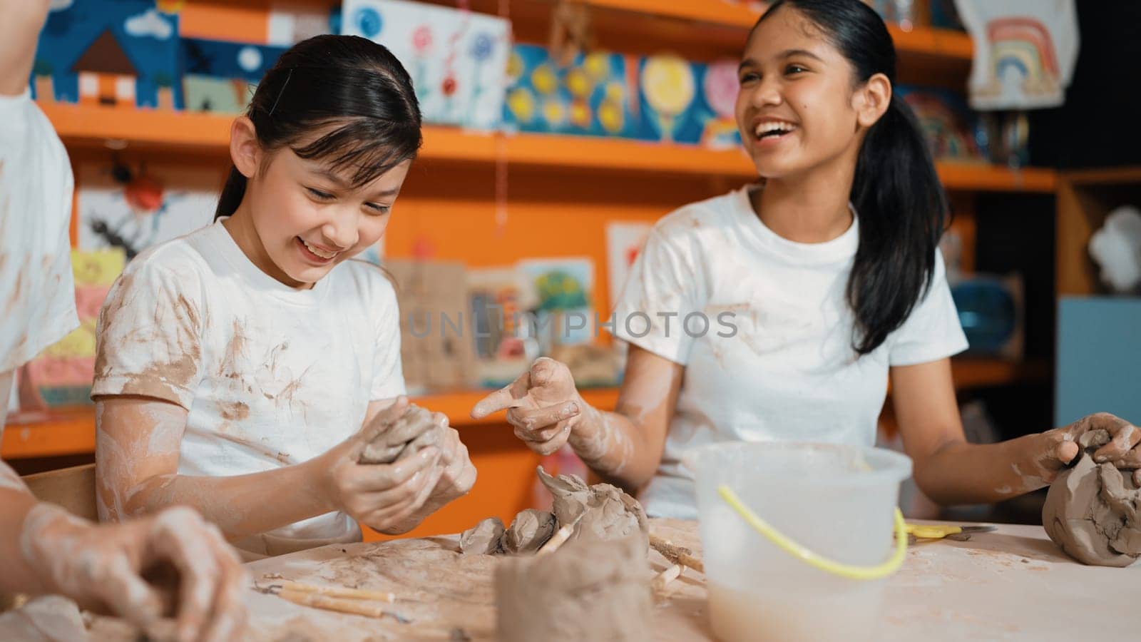 Caucasian highschool girl modeling cup of clay while looking smart boy in art class at workshop. Multicultural student playing or making cup of clay art in creative activity. Education. Edification.