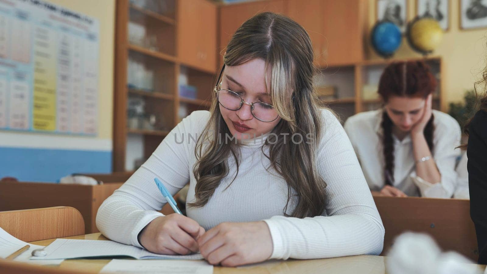 A girl student writes math formulas in a notebook