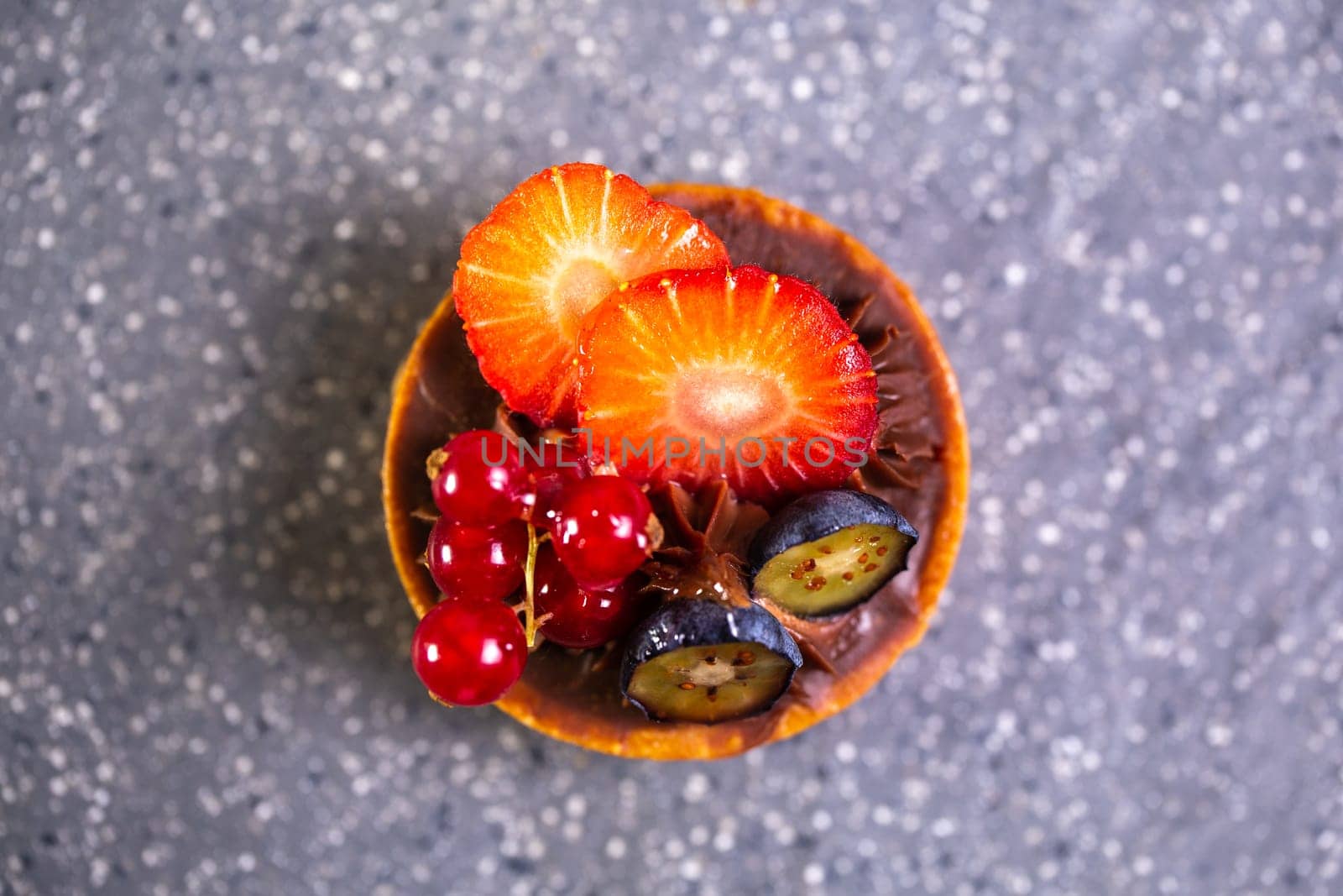 Indulge in a delightful treat of fresh strawberries, blueberries, and red currants atop a rich and decadent chocolate tart.