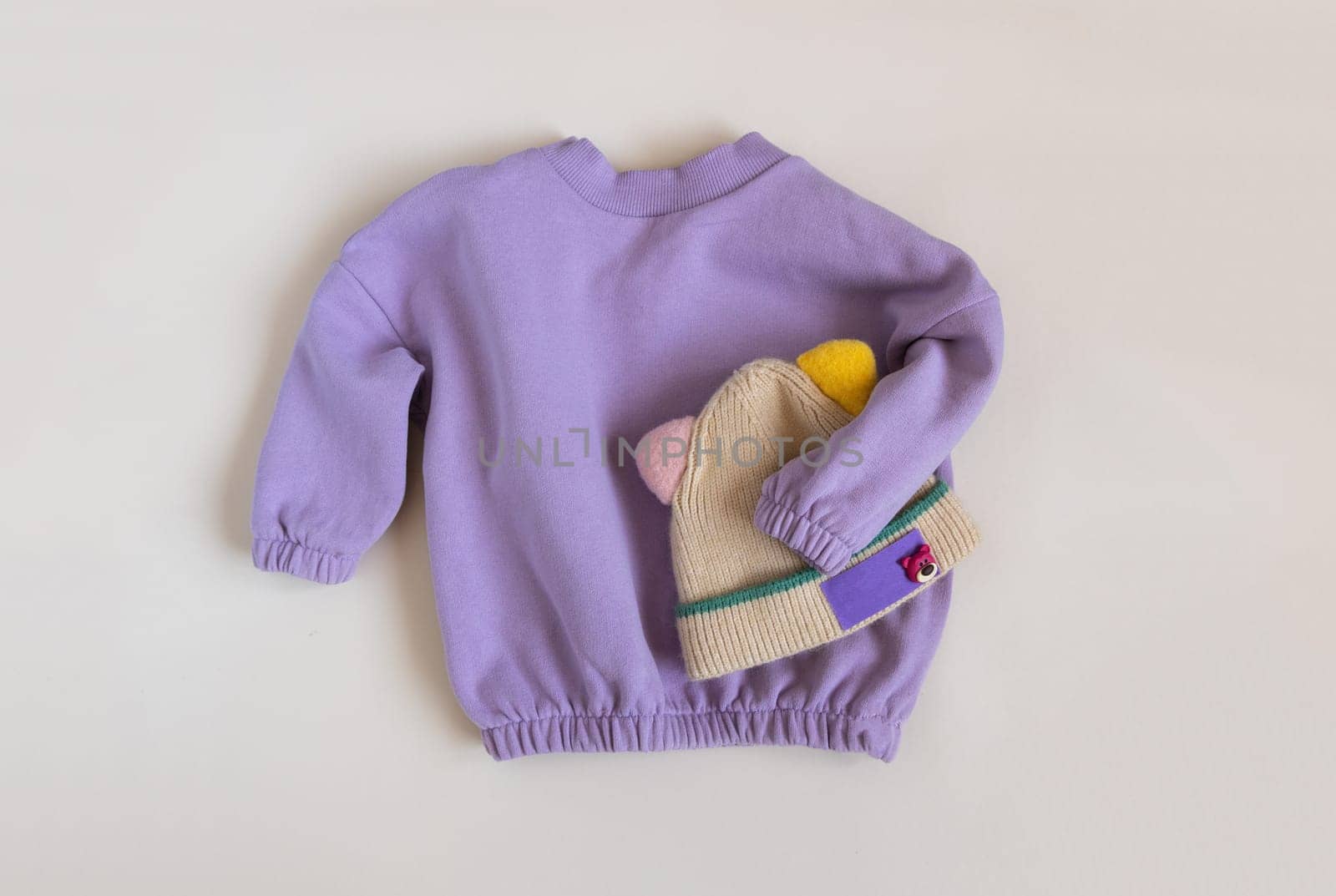 Stylish children's spring lilac sweatshirt and funny hat. Fashion kids outfit for for spring, autumn or winter. Flat lay, top view.