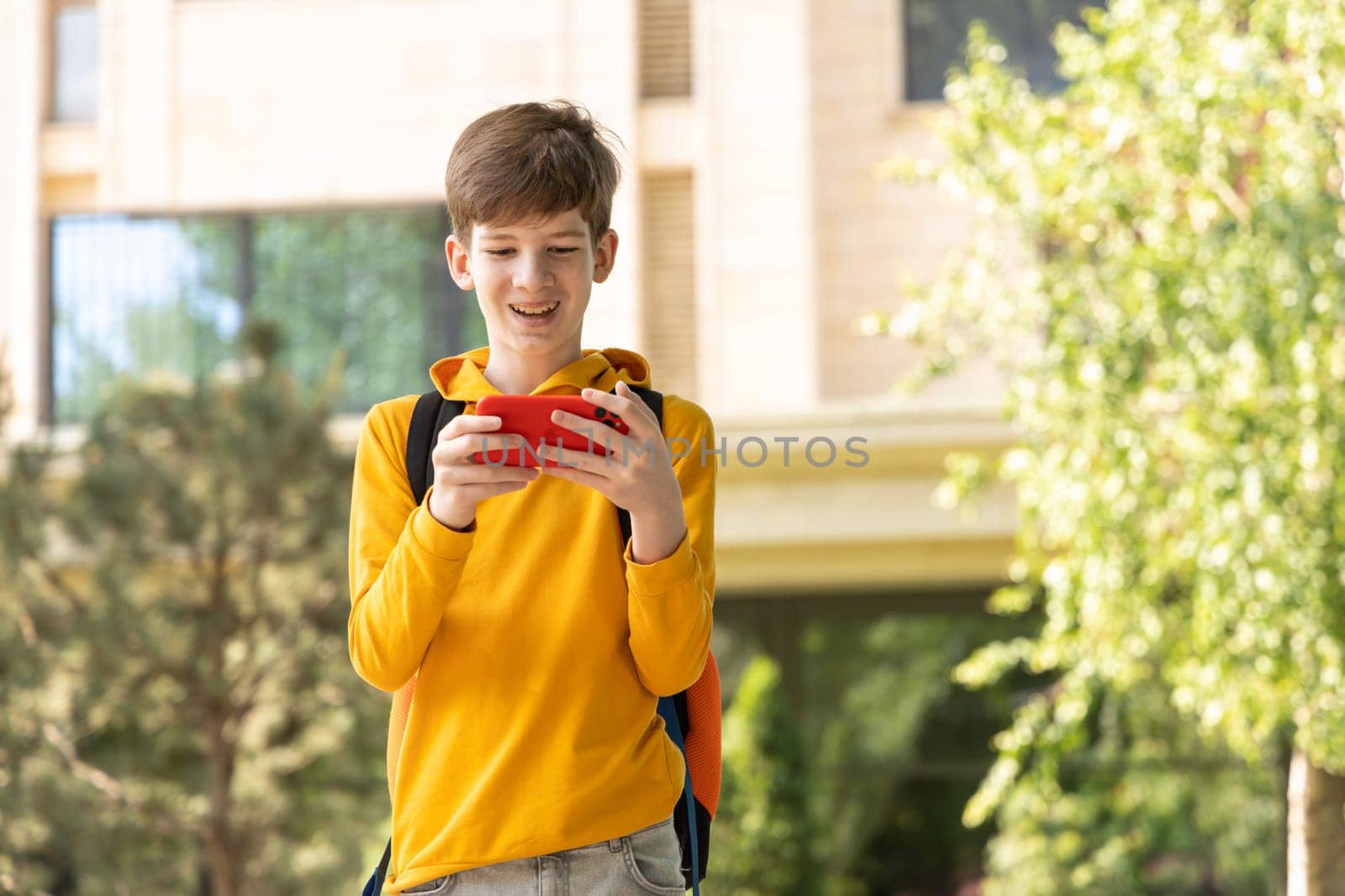 A young boy is having a video call outdoors, holding a smartphone in his hands. by Ri6ka