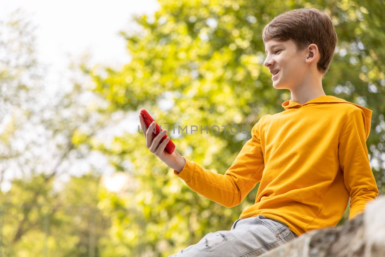 A young boy is having a video call outdoors, holding a smartphone in his hands. by Ri6ka