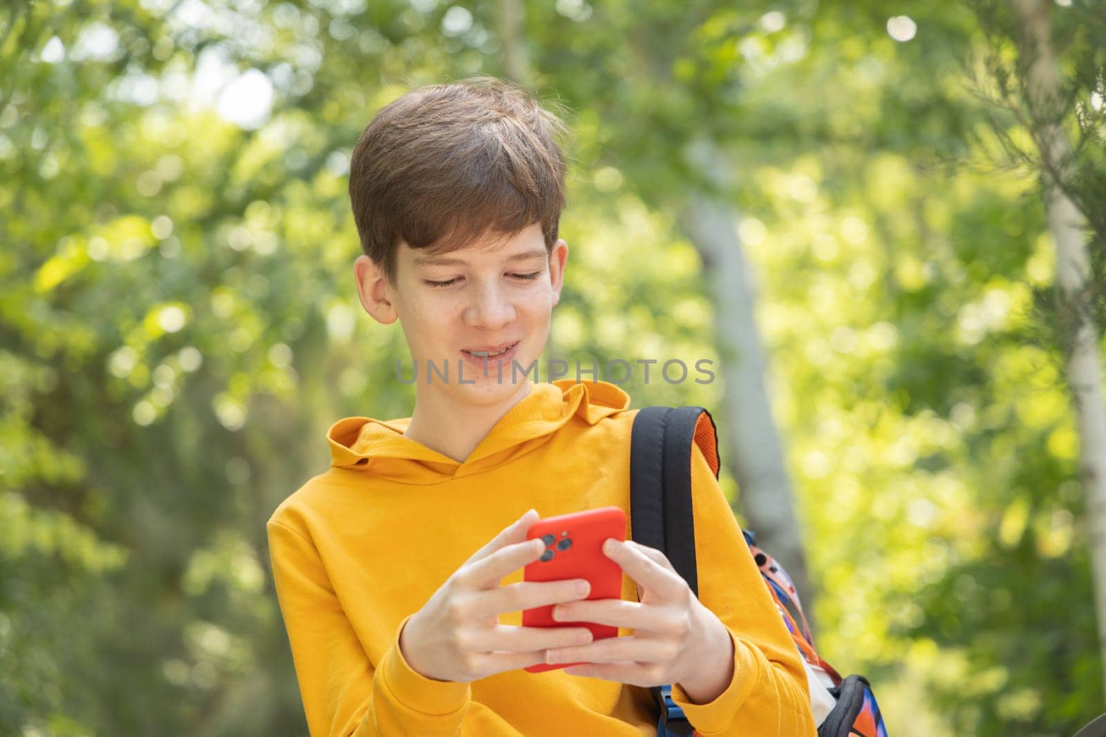 A young boy is having a video call outdoors, holding a smartphone in his hands. by Ri6ka