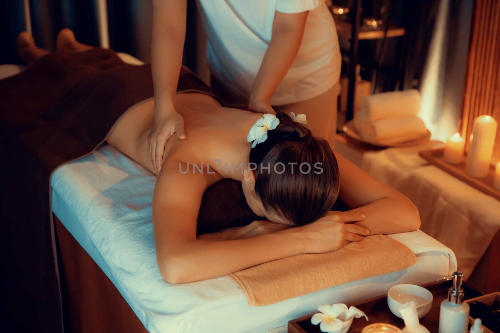 Caucasian woman customer enjoying relaxing anti-stress spa massage and pampering with beauty skin recreation leisure in warm candle lighting ambient salon spa at luxury resort or hotel. Quiescent