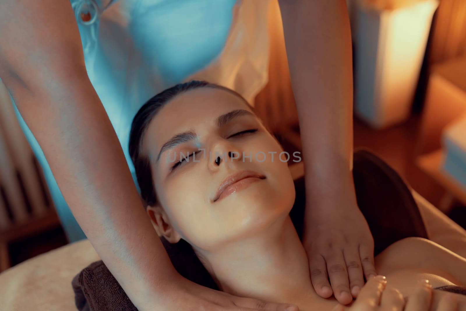 Caucasian woman customer enjoying relaxing anti-stress spa massage and pampering with beauty skin recreation leisure in warm candle lighting ambient salon spa at luxury resort or hotel. Quiescent