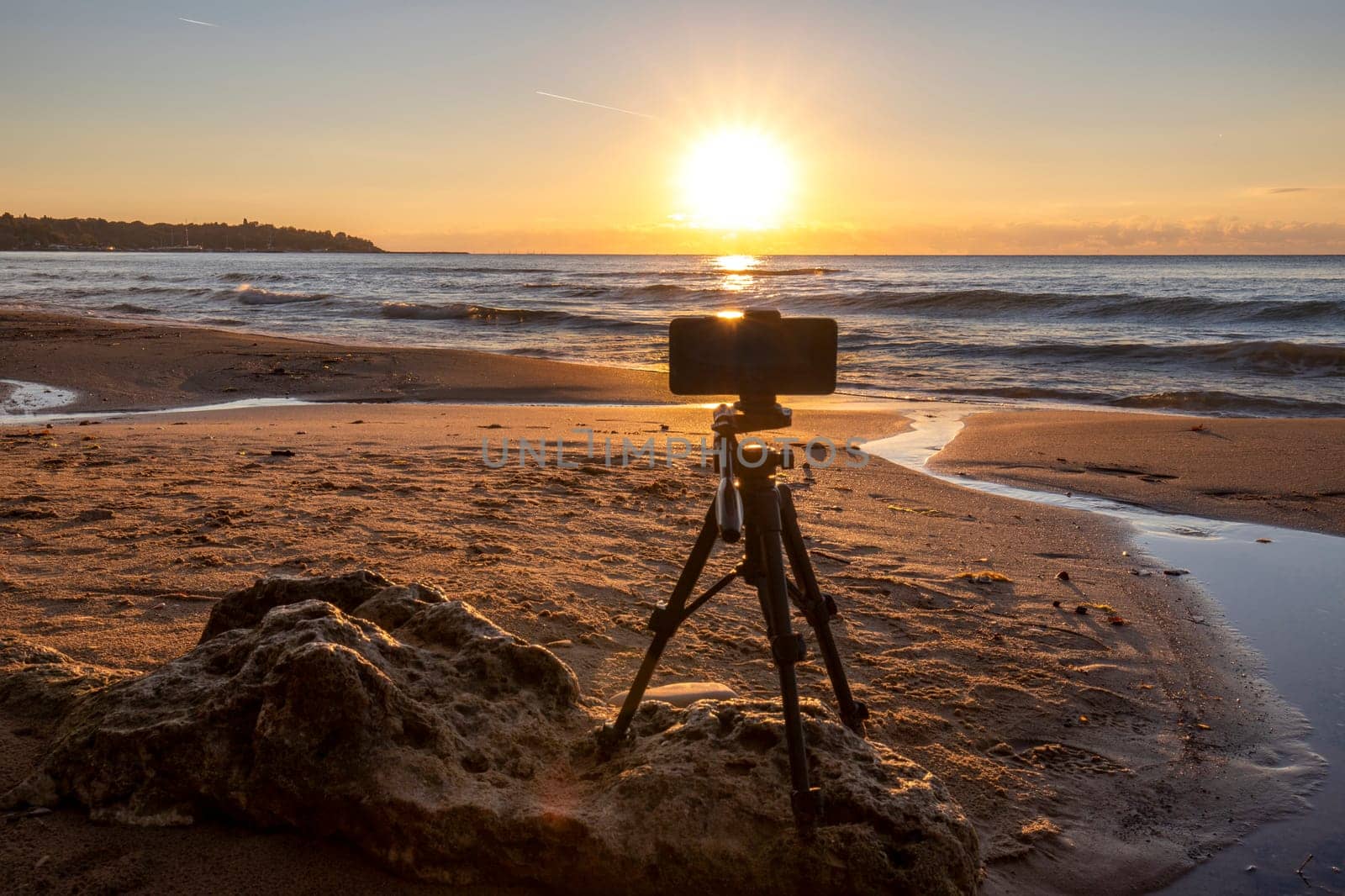 A telephone on a tripod standing on the beach shooting sunrise by EdVal