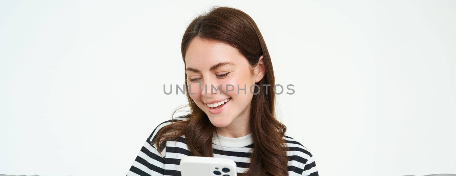 Portrait of girl with smartphone laughing, using mobile phone app, isolated on white background.