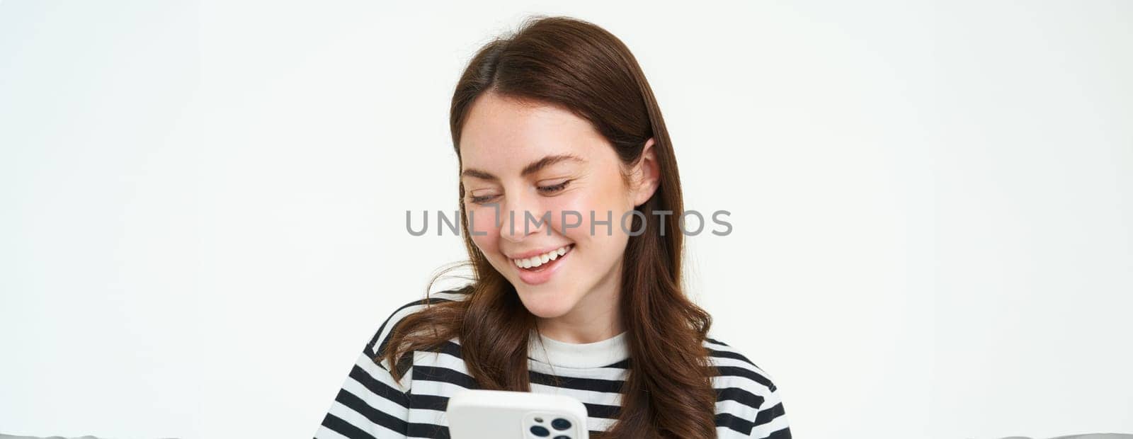 Portrait of girl with smartphone laughing, using mobile phone app, isolated on white background by Benzoix