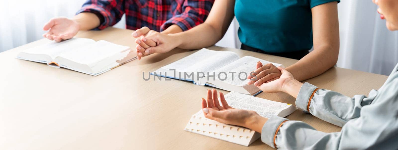 Cropped image of diversity people hand praying together at wooden church on bible book. Group of believer hold hand together faithfully. Concept of hope, religion, faith, god blessing. Burgeoning.