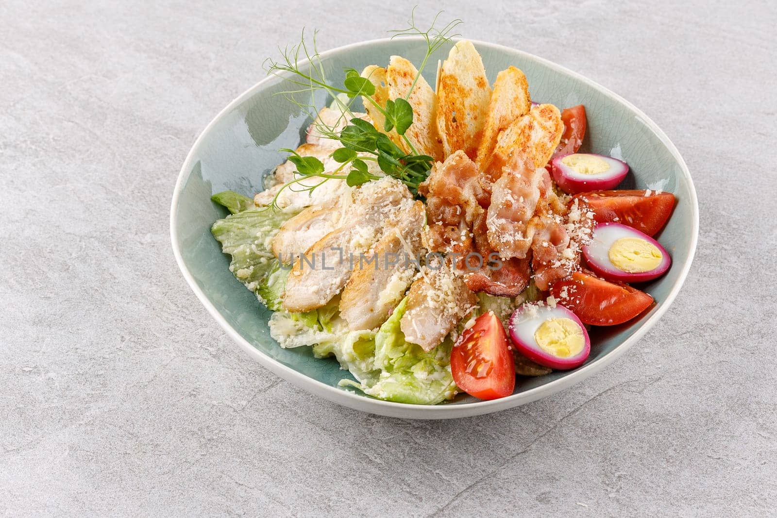 Caesar salad with chicken and bacon on a stone background studio food photo 1