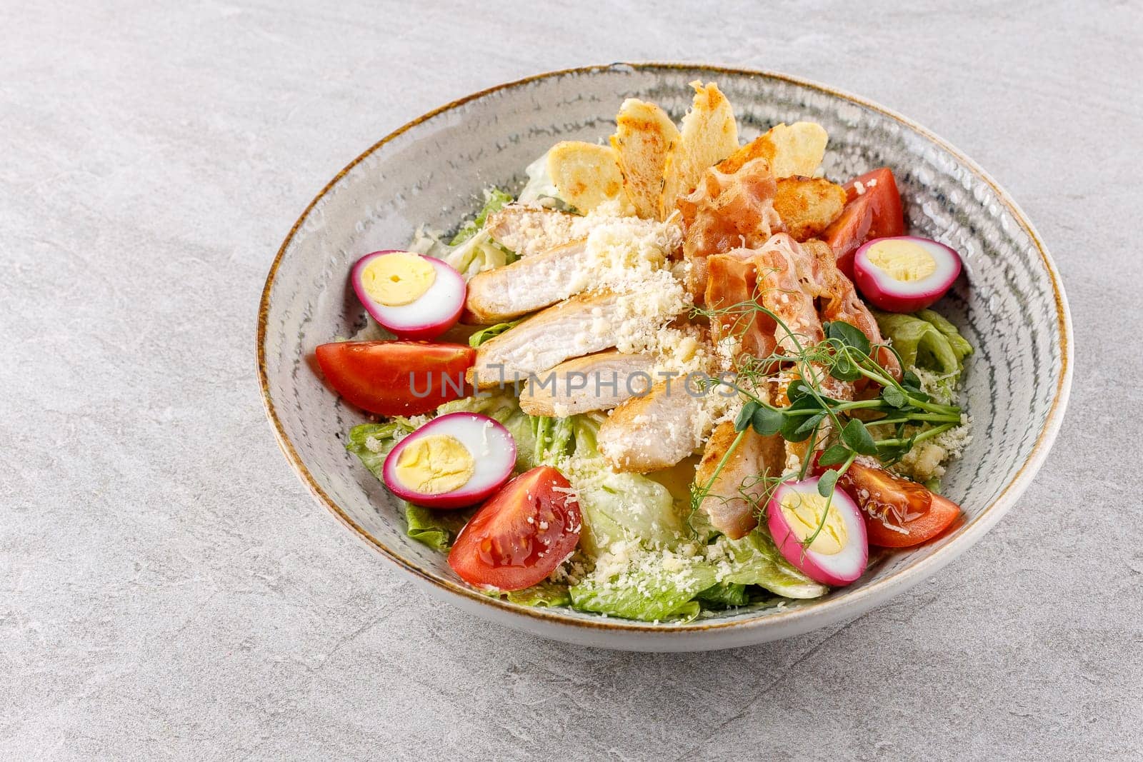 Caesar salad with chicken and bacon on a stone background studio food photo