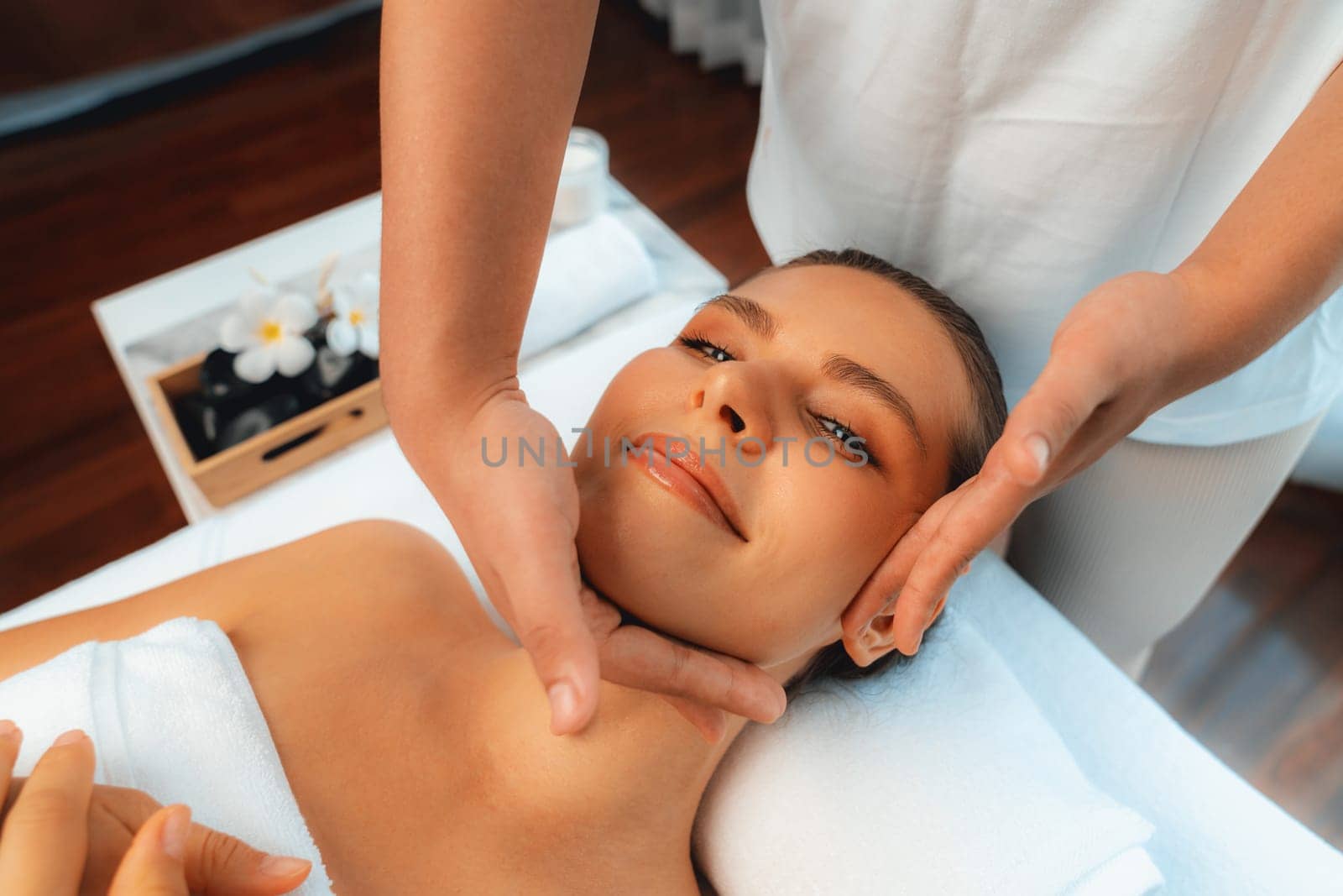 Caucasian woman enjoying relaxing anti-stress head massage and pampering facial beauty skin recreation leisure in dayspa modern light ambient at luxury resort or hotel spa salon. Quiescent