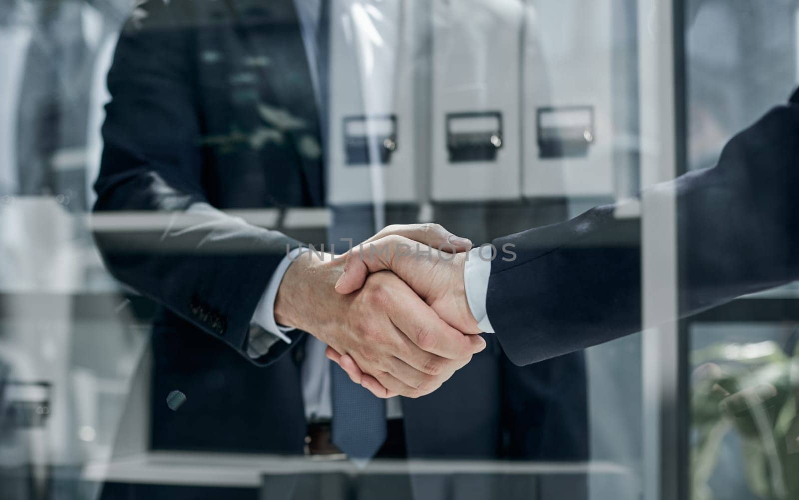 Two business people shaking hands in front of their colleagues