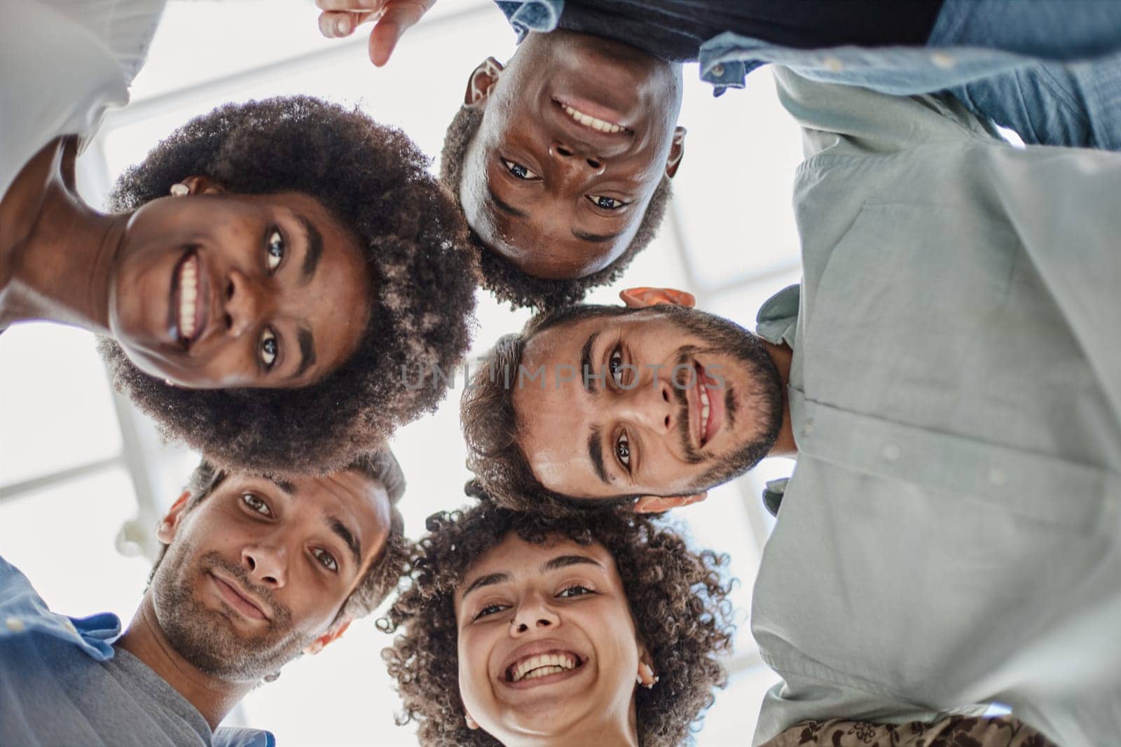 Closeup portrait, bottom view, happy faces of different team employees standing in circle.