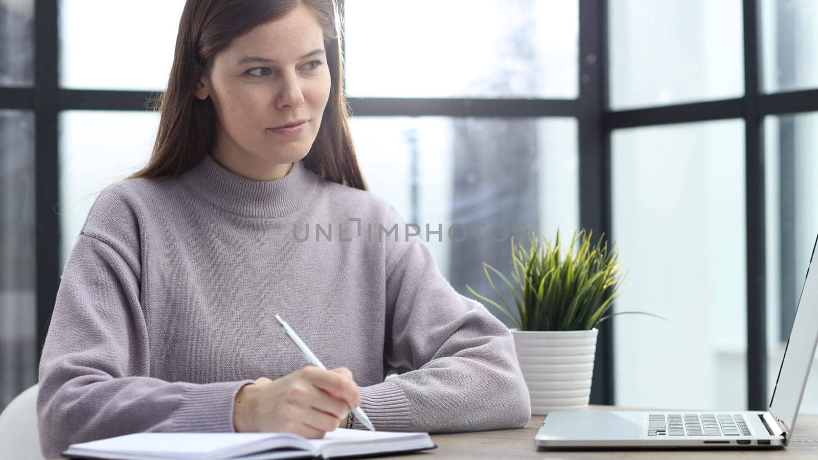 A woman in close-up at a desk in the office working with documents and keeping a report.