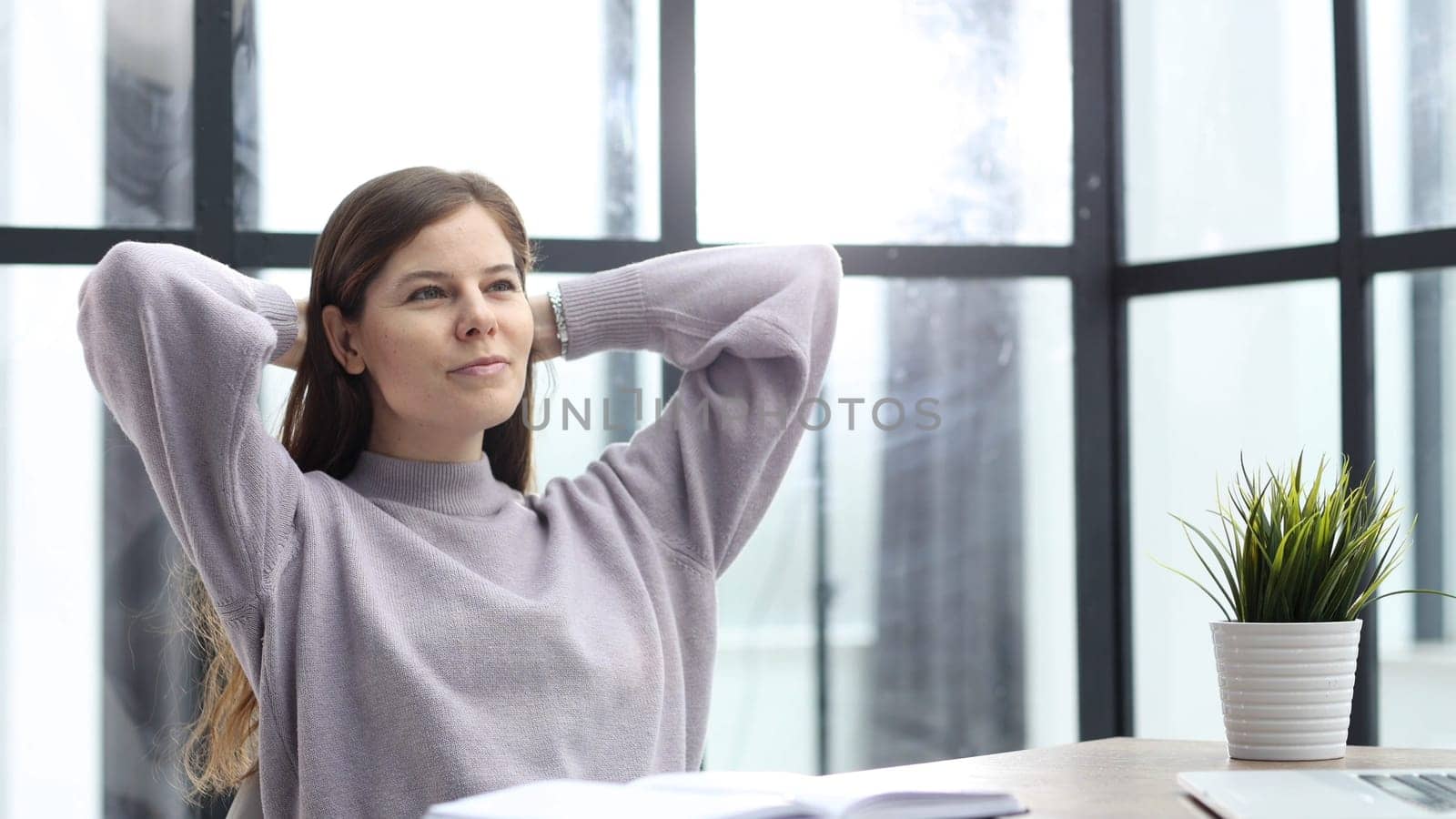 A woman in close-up at a desk in the office resting after work.