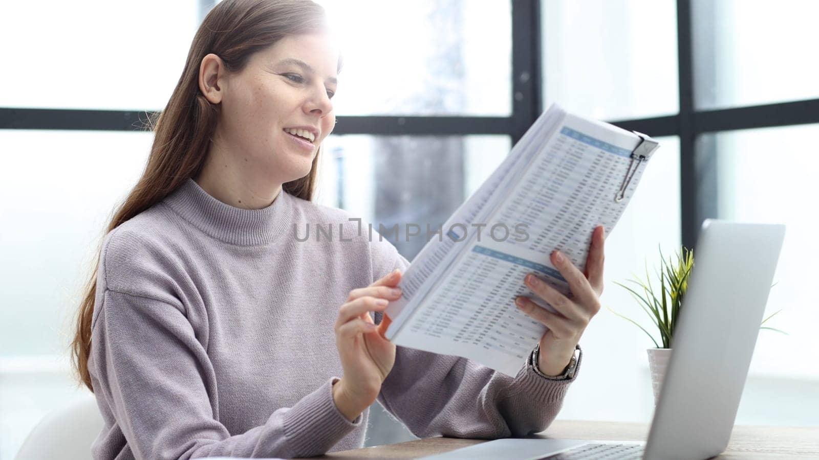 A woman in close-up at a desk in the office checks the report.