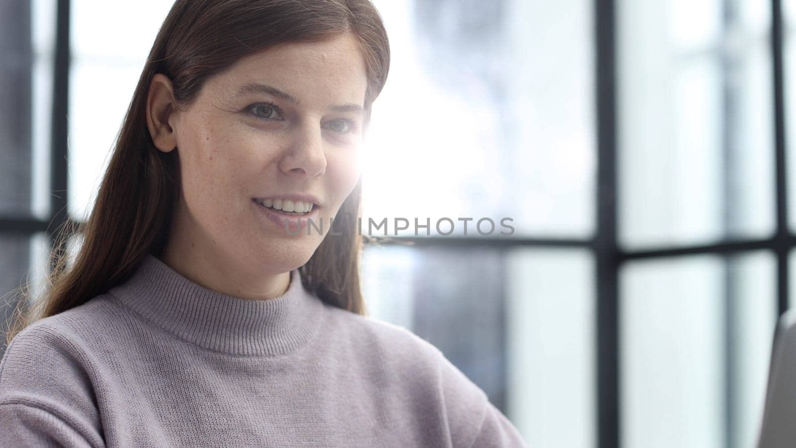 A woman in close-up in the office working and looking ahead.