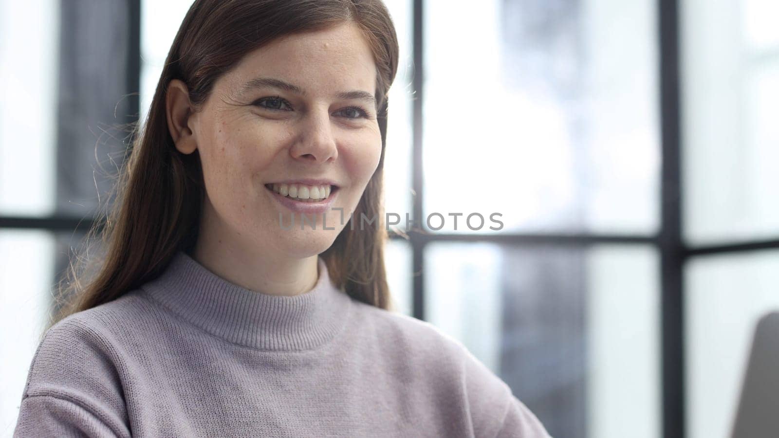 A woman's face is in close-up in the office, she is working on a laptop.