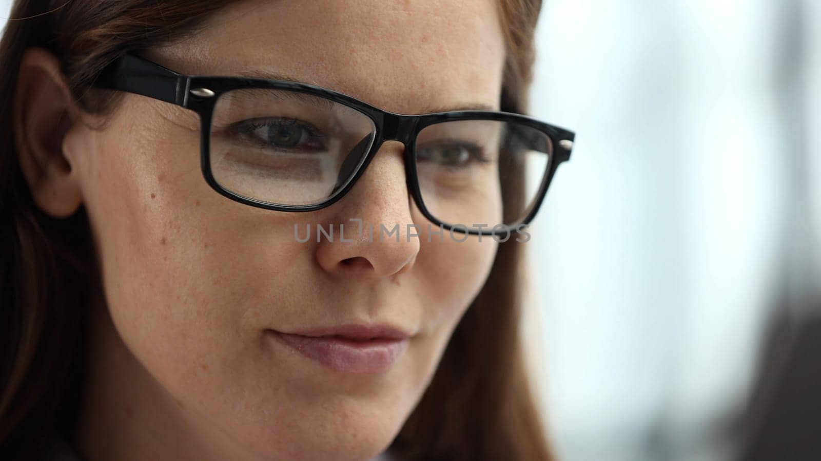Close-up of a woman's face in the office with glasses.