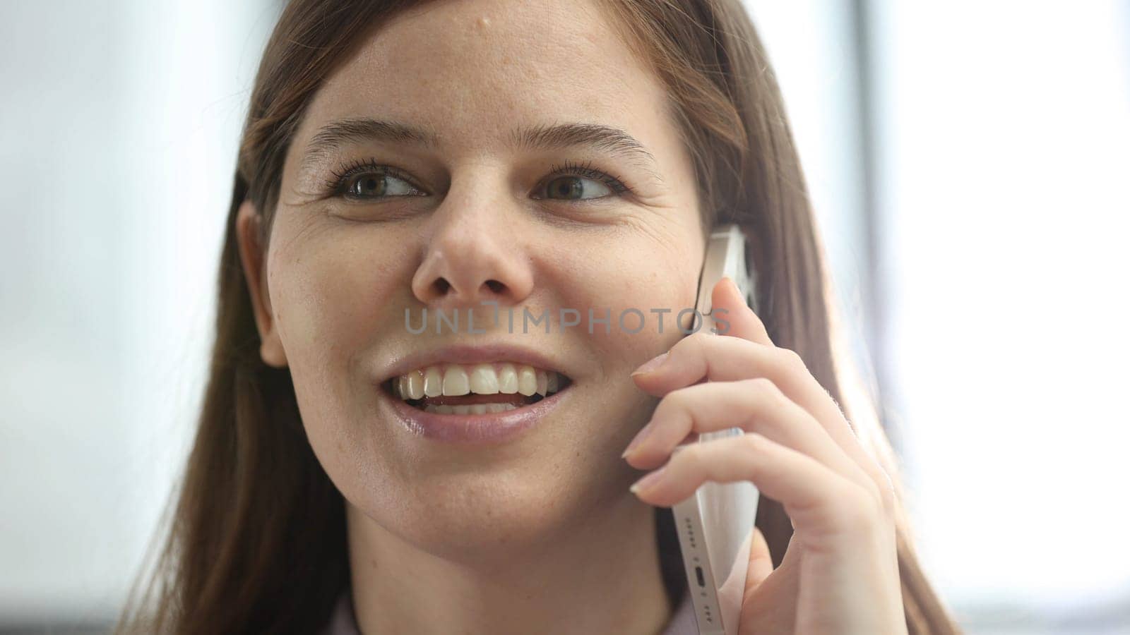 A woman's face is in close-up in the office, she is talking on the phone about a business decision.