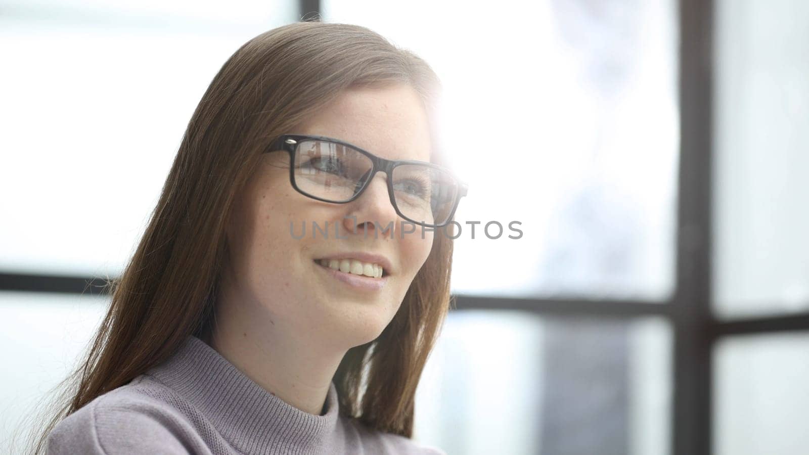 The face of a woman with glasses in close-up in the office.
