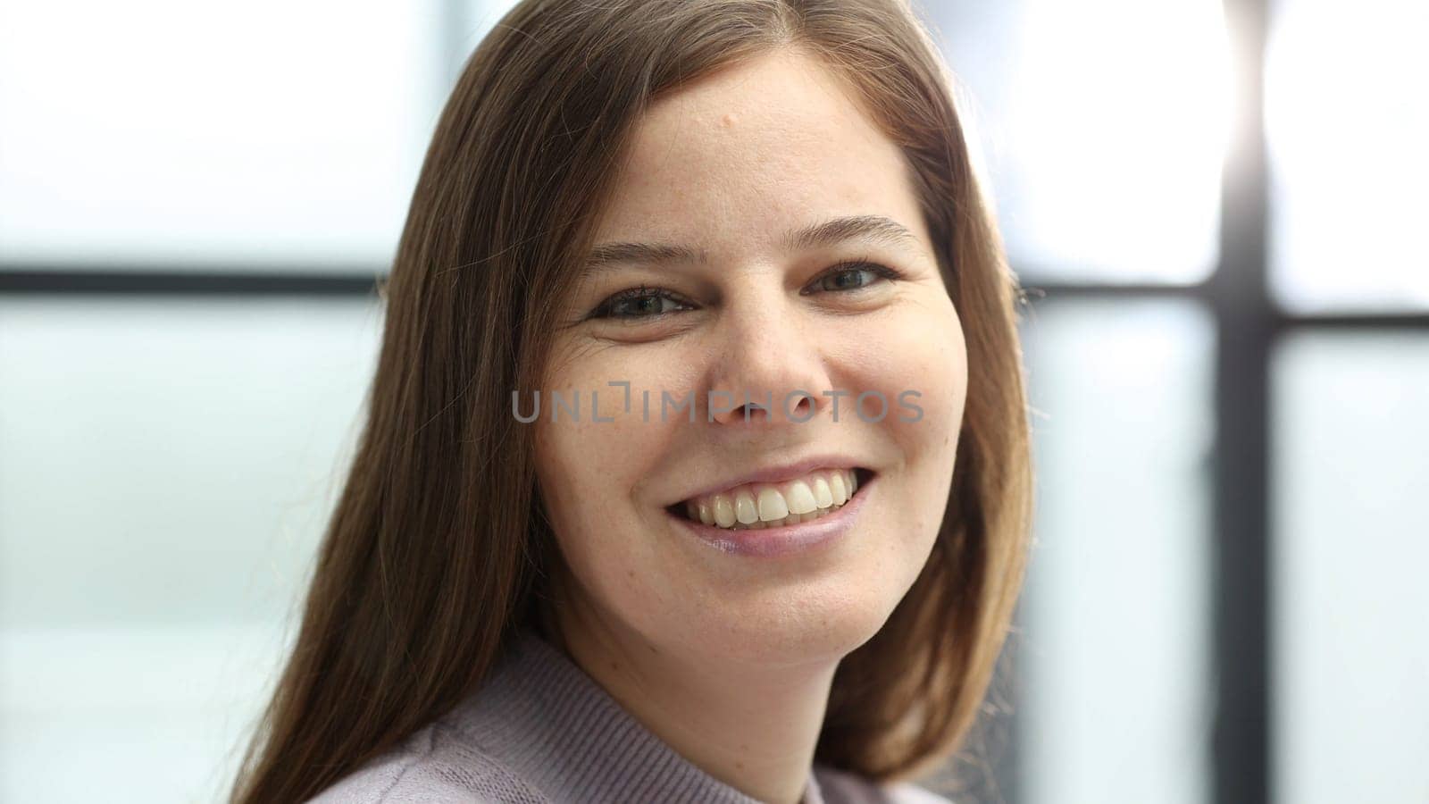 A woman's face in close-up in the office, she looks at the camera.
