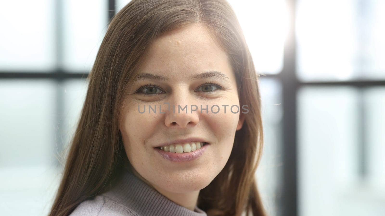 A woman's face in close-up in the office, she looks at the camera.