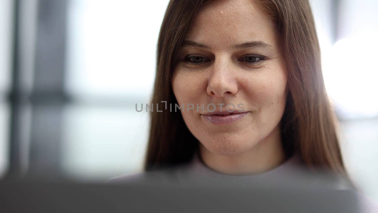 Close-up of a woman working at a desk in an office on a laptop.