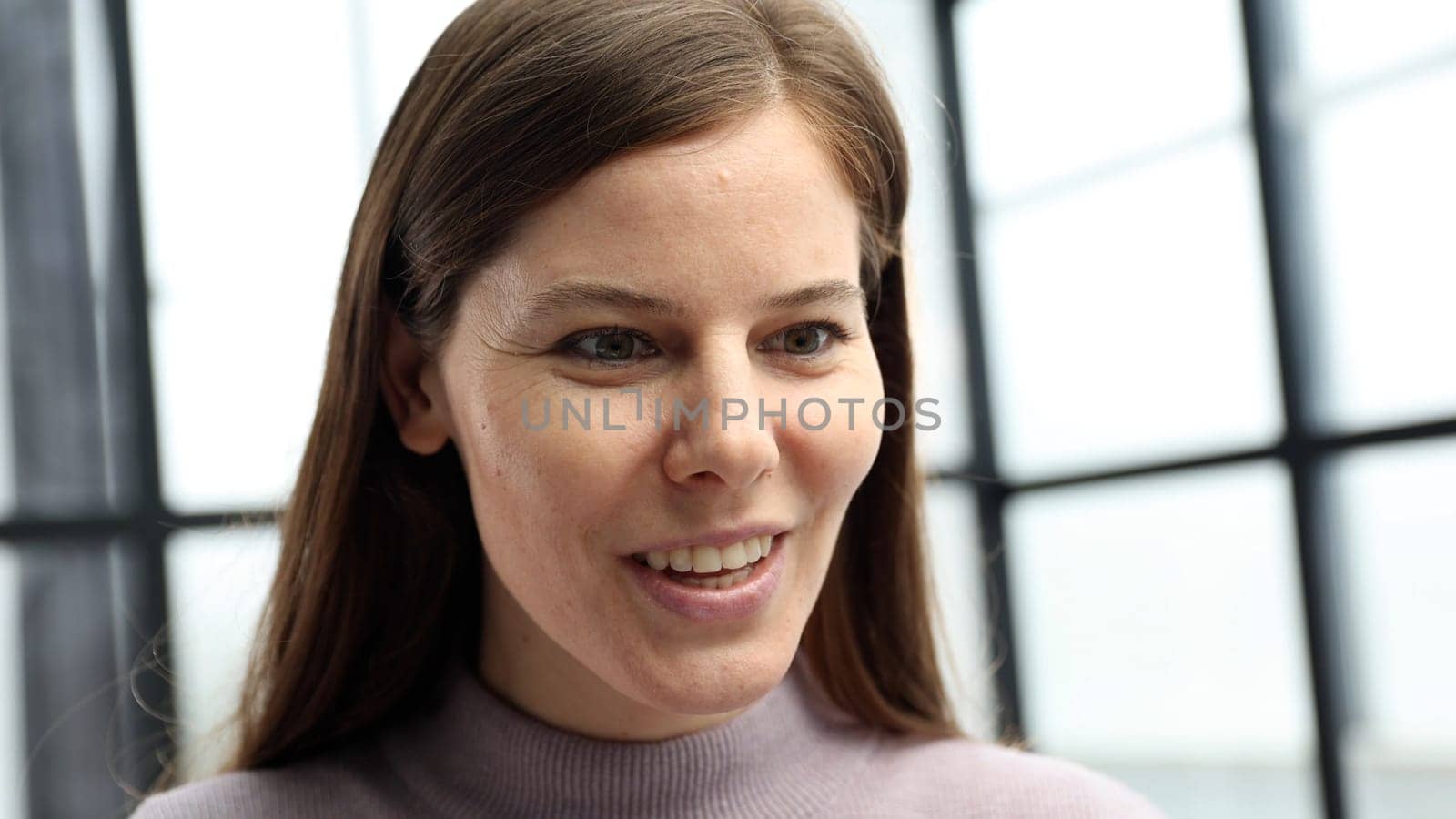 A woman's face is in close-up in the office, she looks at the screen and is surprised.