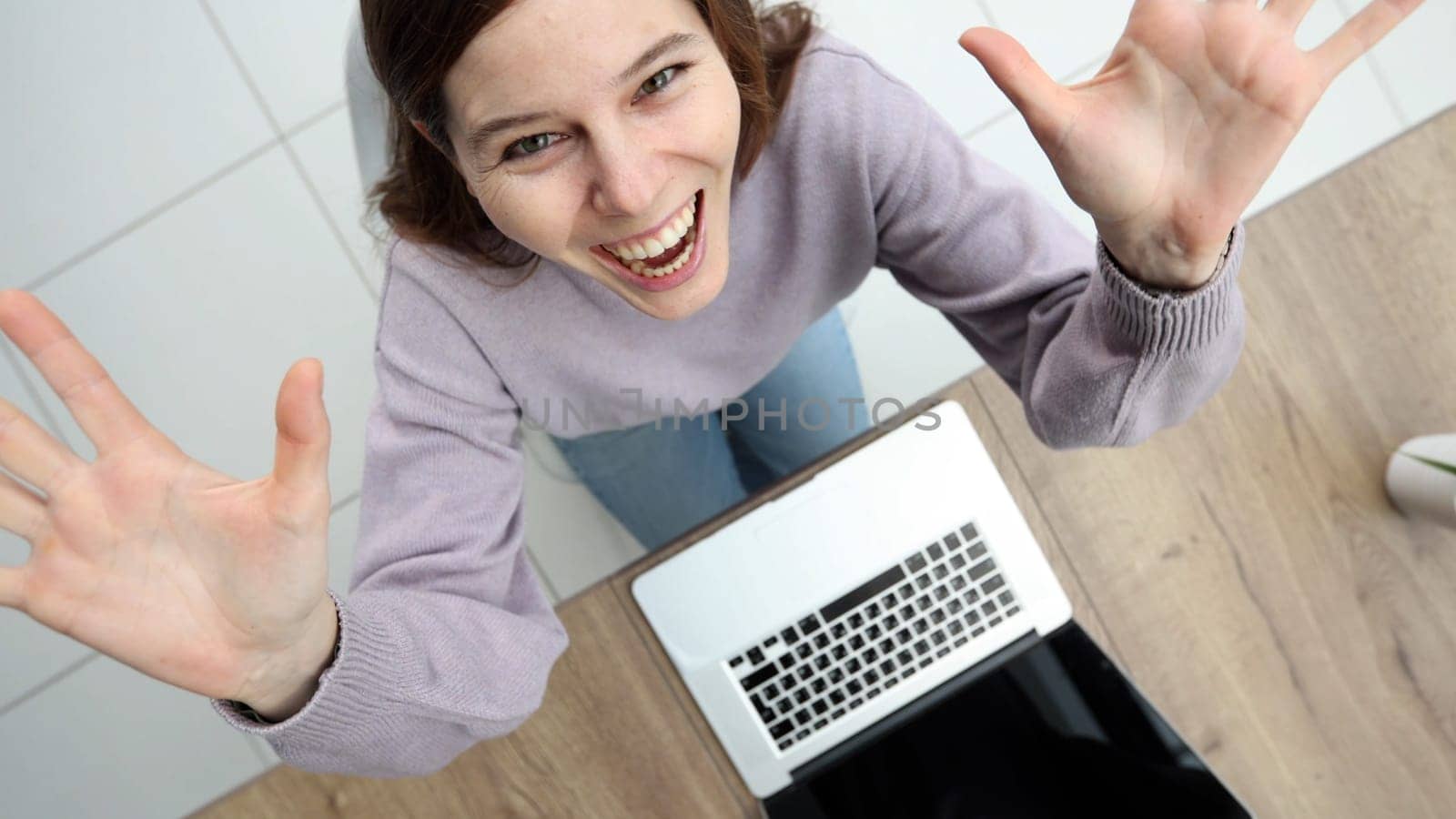 A woman in close-up in the office at a desk working with a laptop, she rejoices at a successful deal.