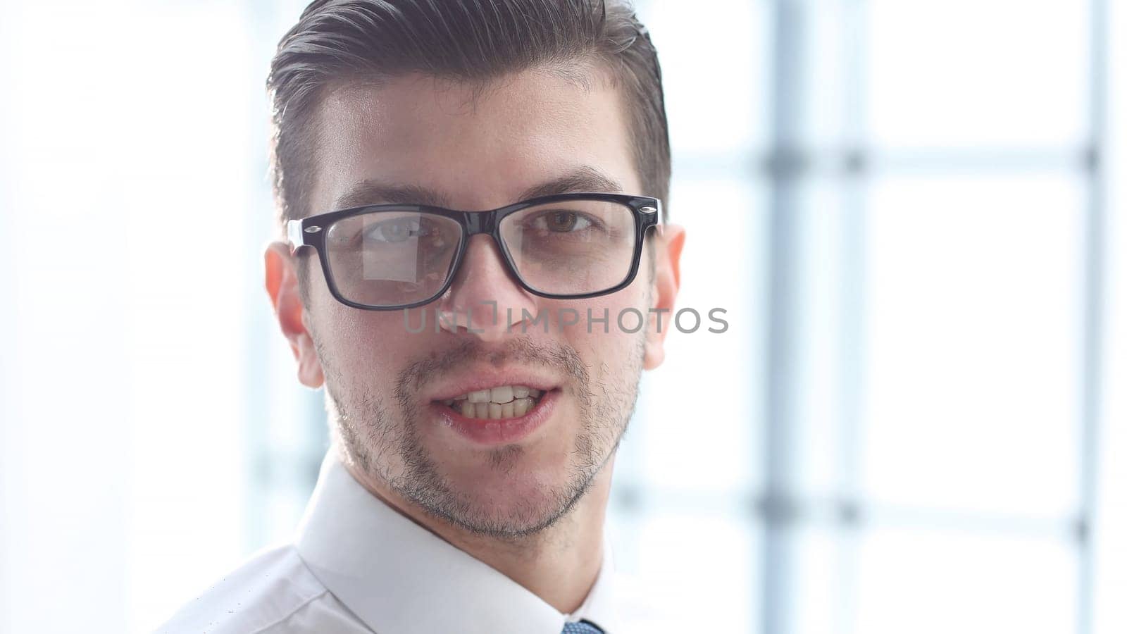 A male office worker looks at the camera in close-up.