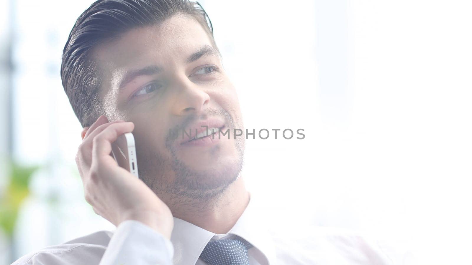A businessman man is talking on the phone in close-up.