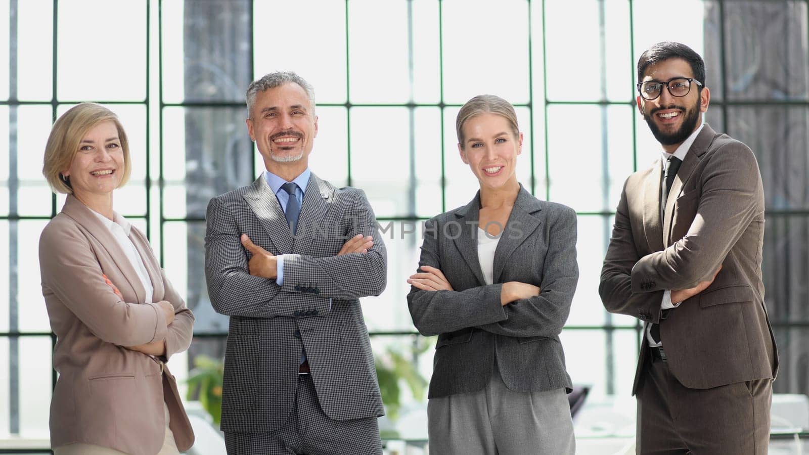 a team of businessmen stand in a trendy office with their arms crossed. business concept