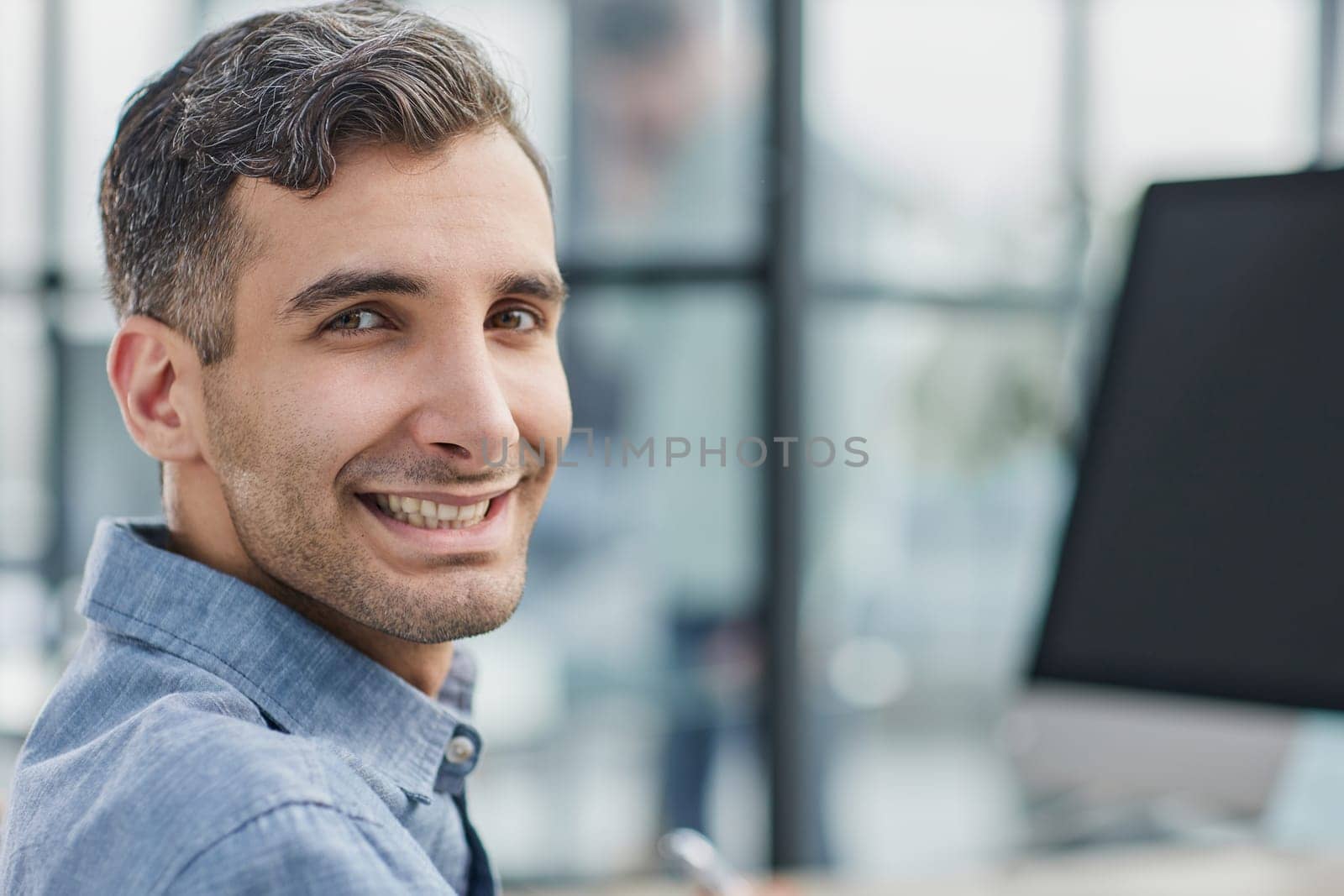 Portrait of cheerful male student enjoying learning in coworking office using laptop computer for research