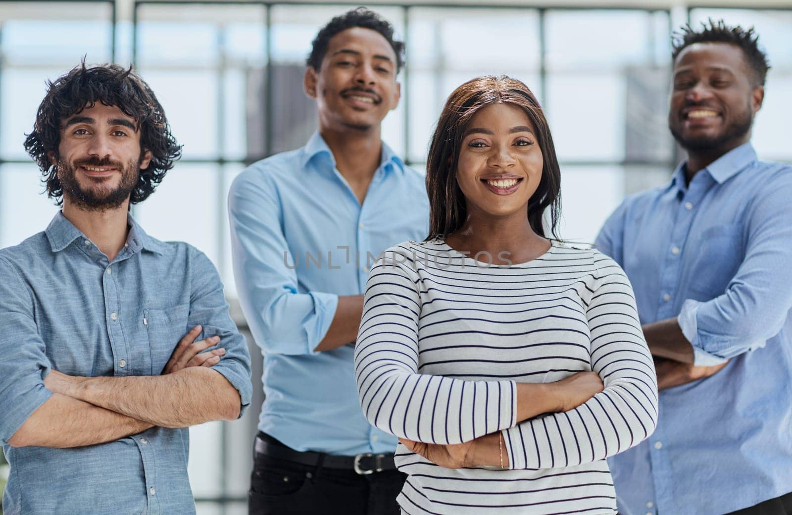 Group of professionals in businesswear, smiling and standing with arms crossed in office.