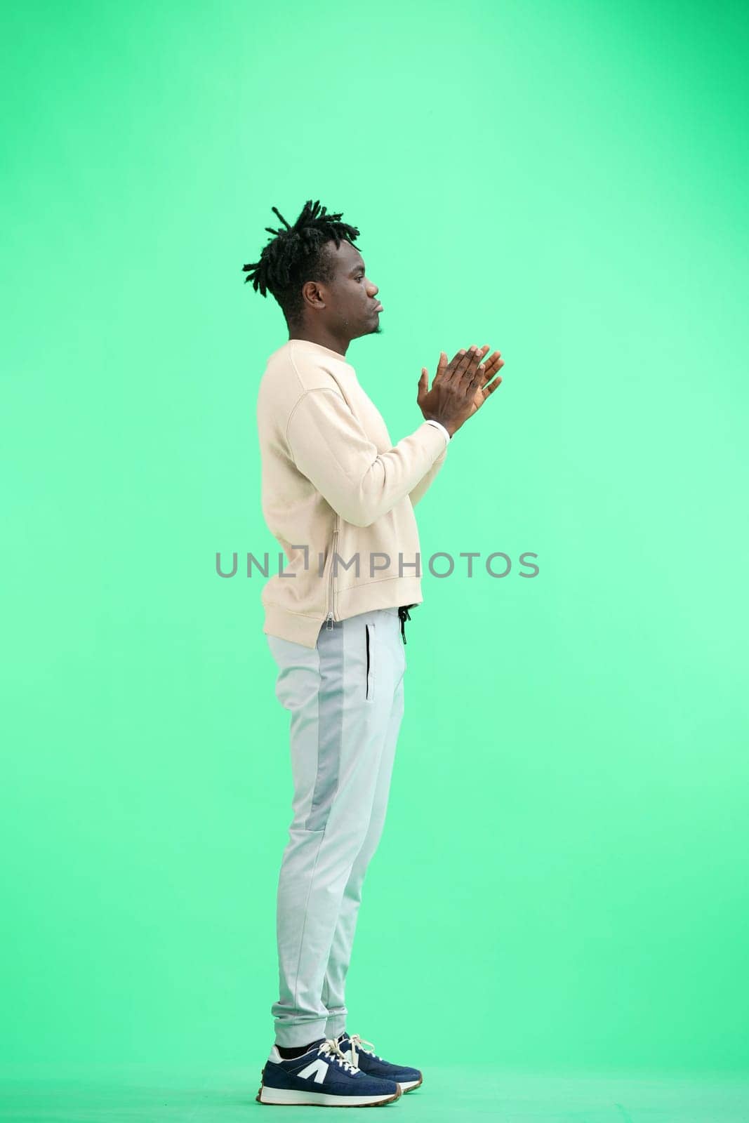 A man, full-length, on a green background, claps.