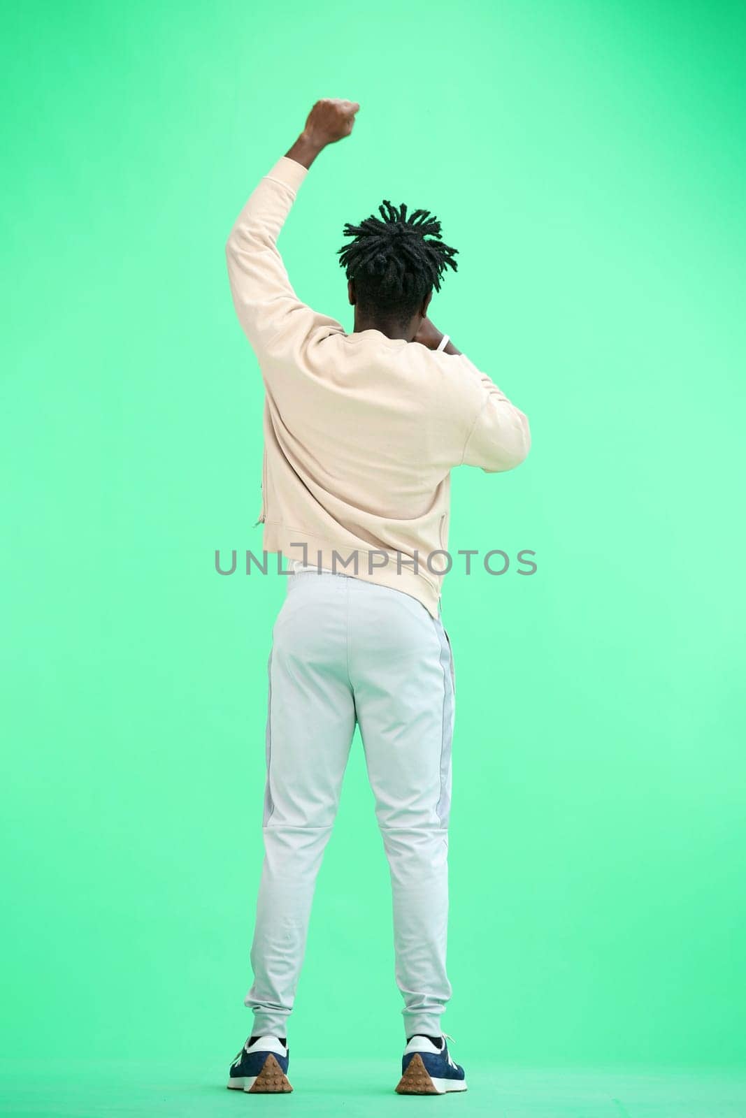 A man, full-length, on a green background, rejoices.