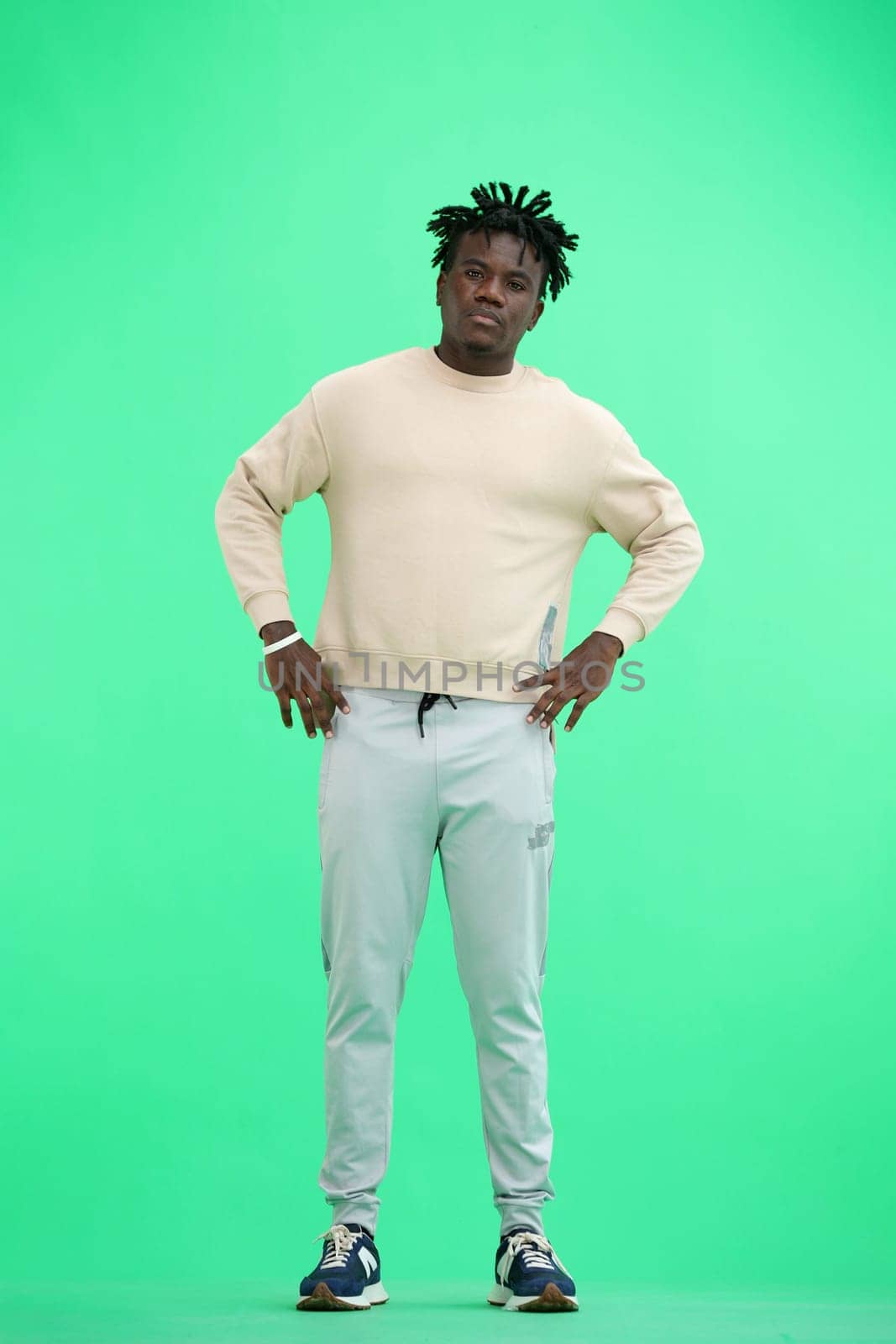 Man, full-length, on a green background, hands on his belt.