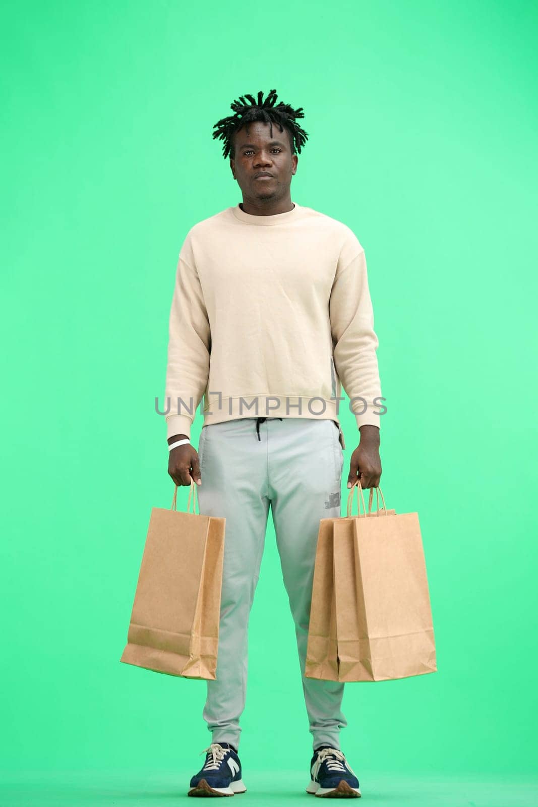 A man, full-length, on a green background, with bags.