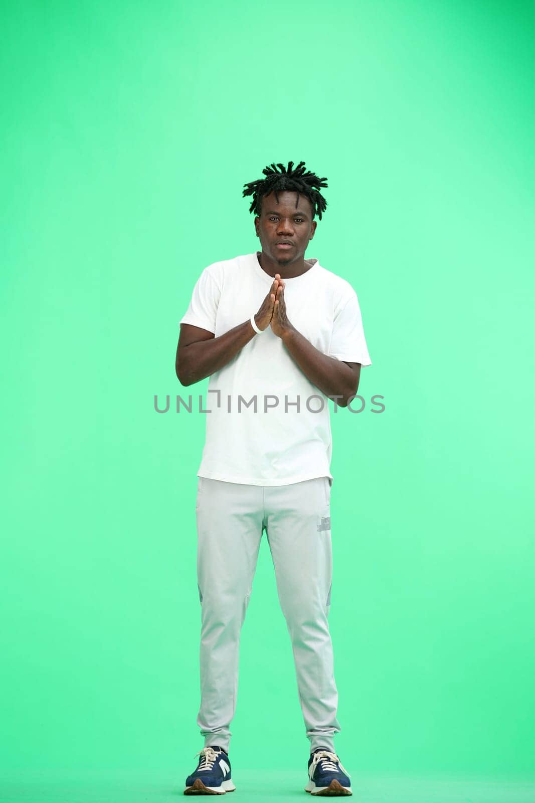 A man, full-length, on a green background, folded his arms.
