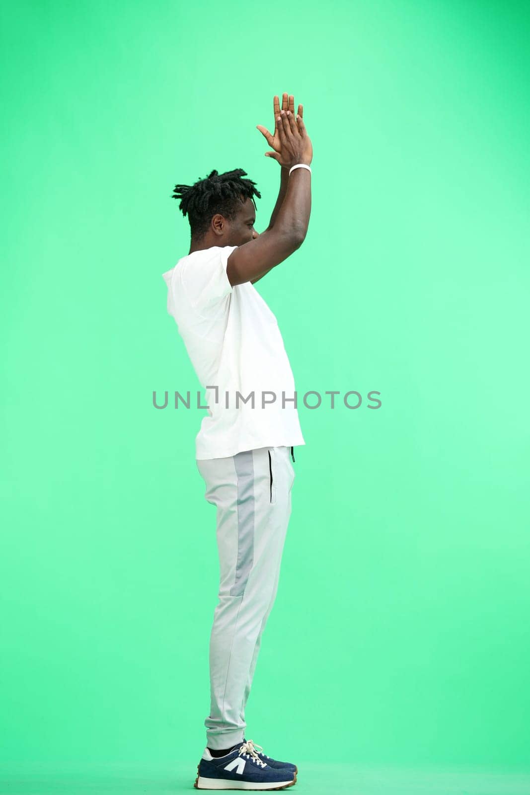 A man, full-length, on a green background, claps.