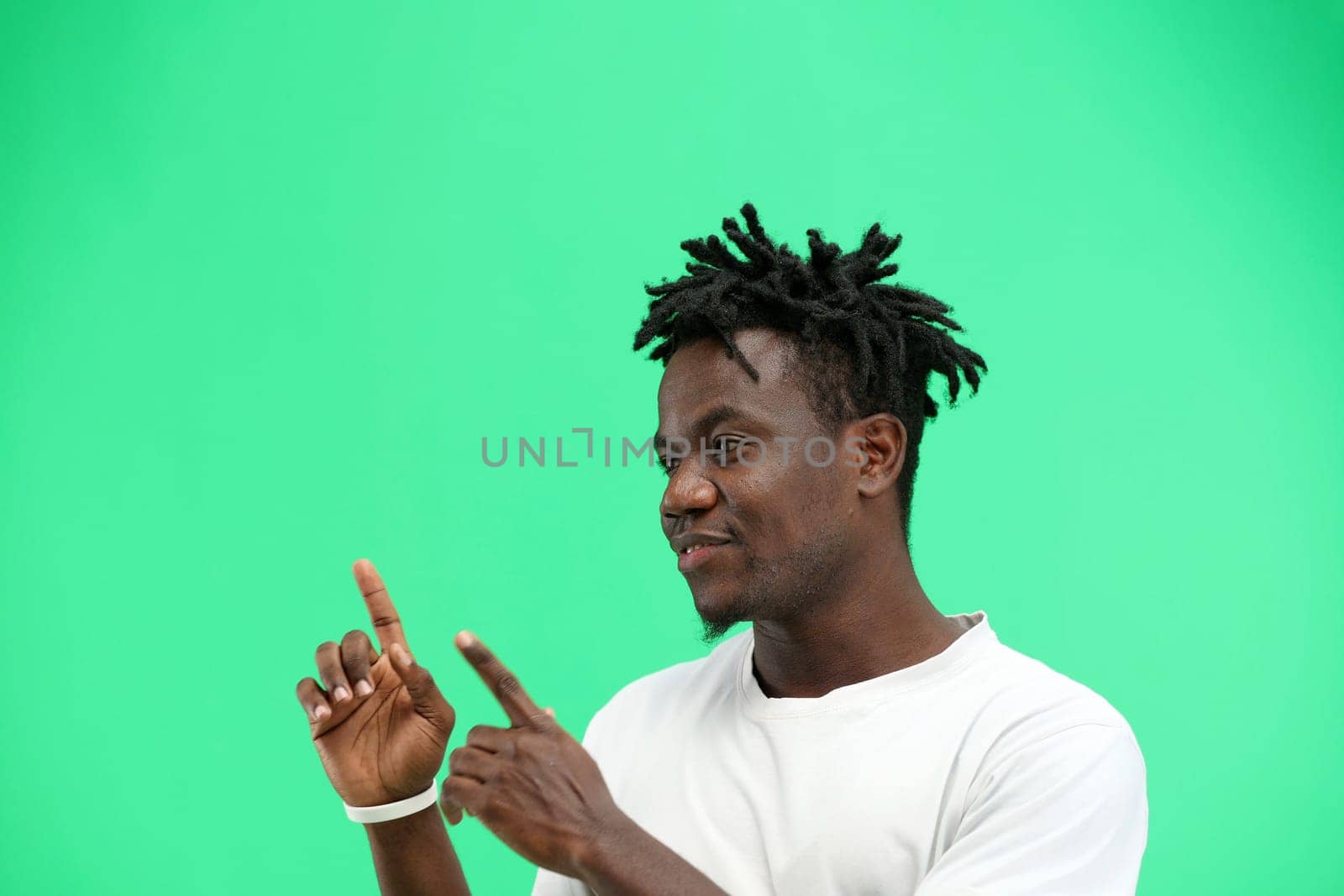 A man, close-up, on a green background, points to the side.
