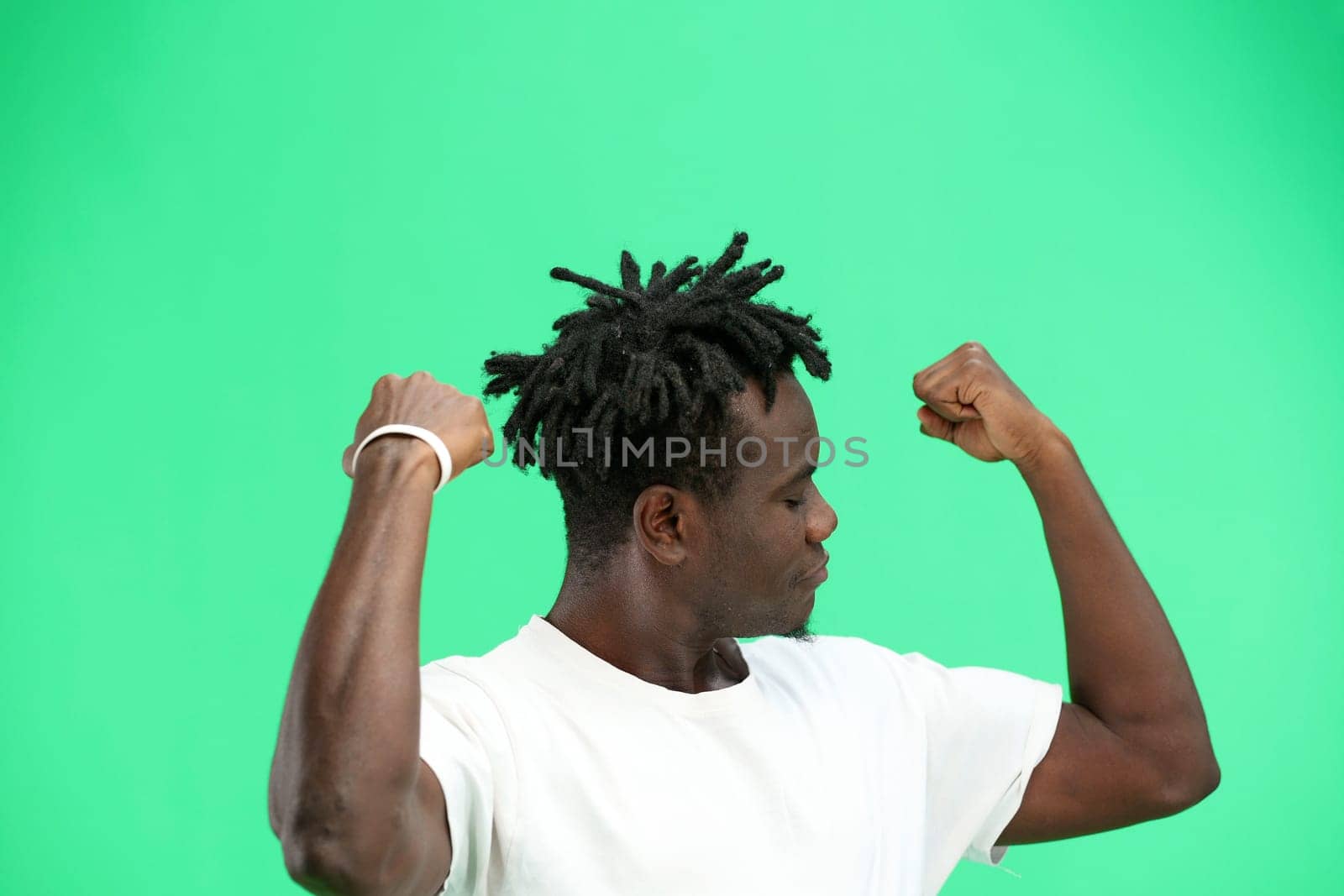 Man, close-up, on a green background, shows strength.