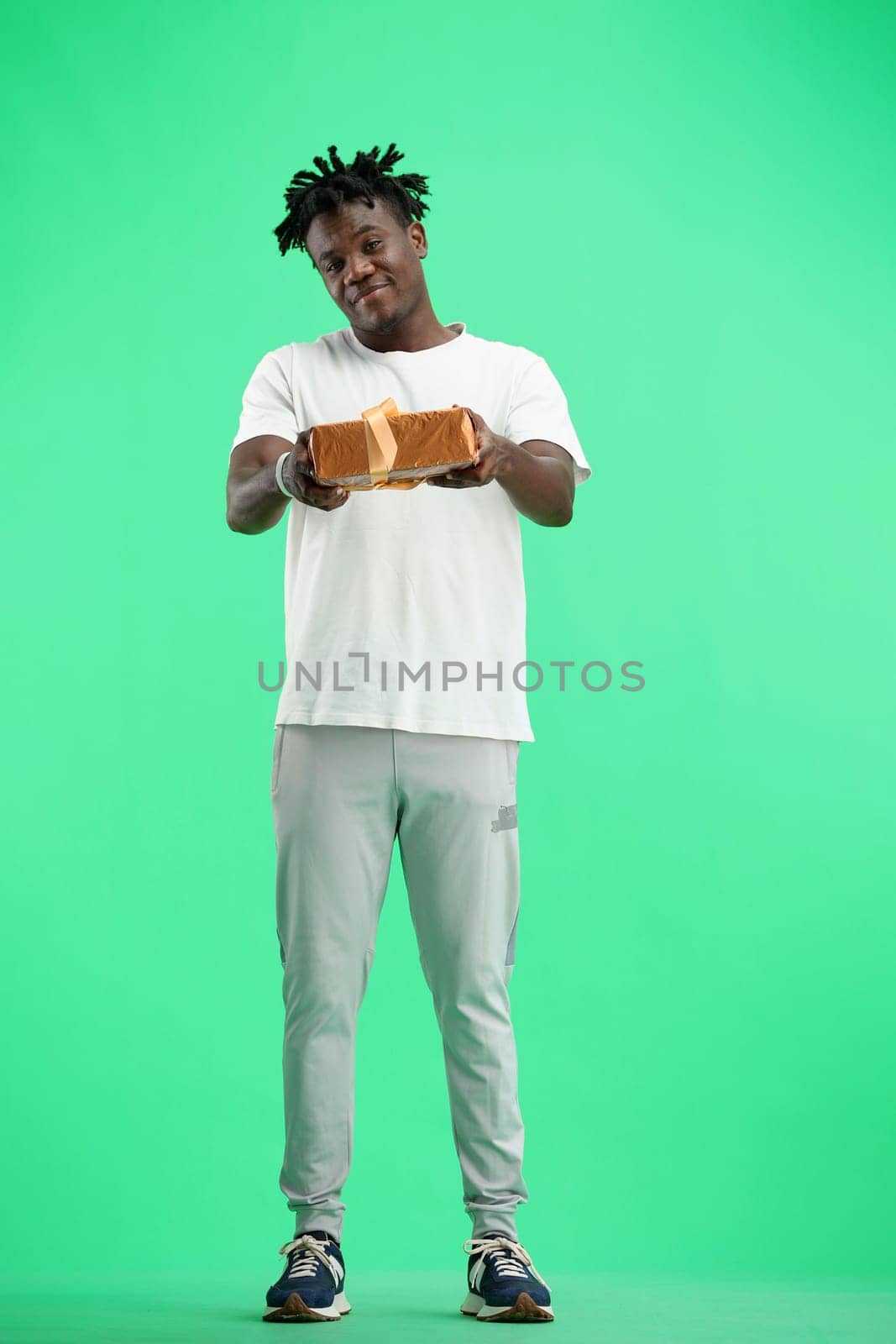 A man, full-length, on a green background, with a gift.