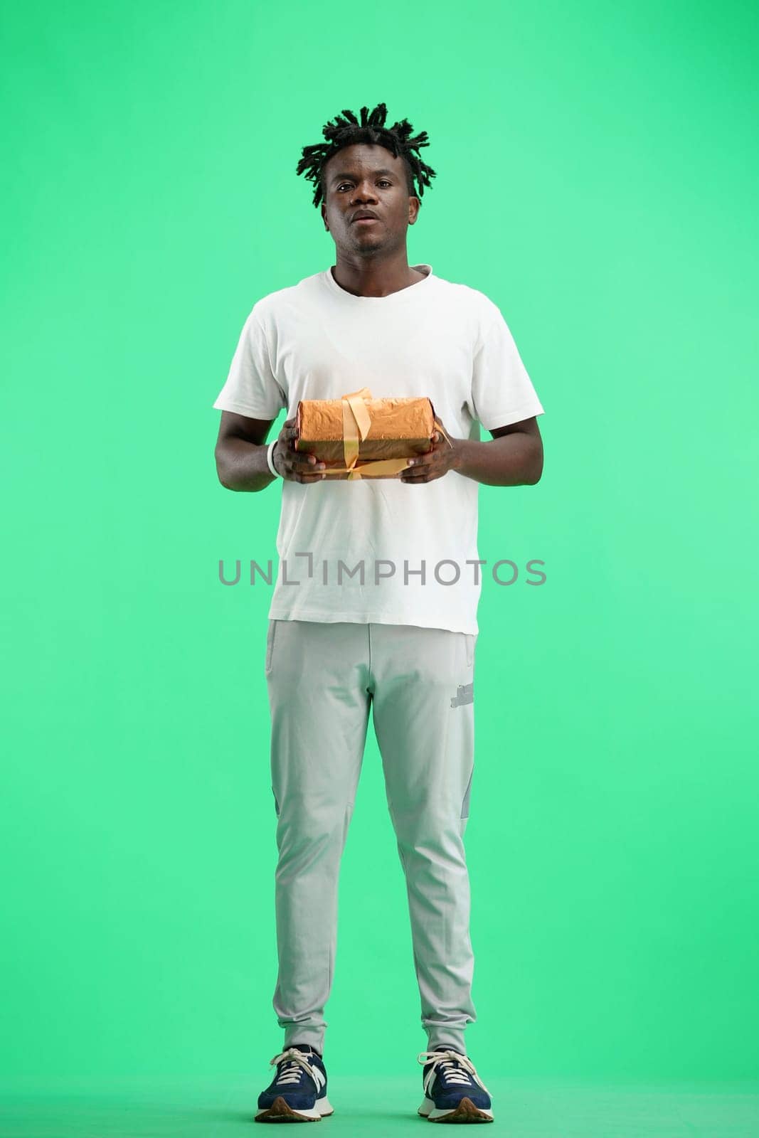 A man, full-length, on a green background, with a gift.