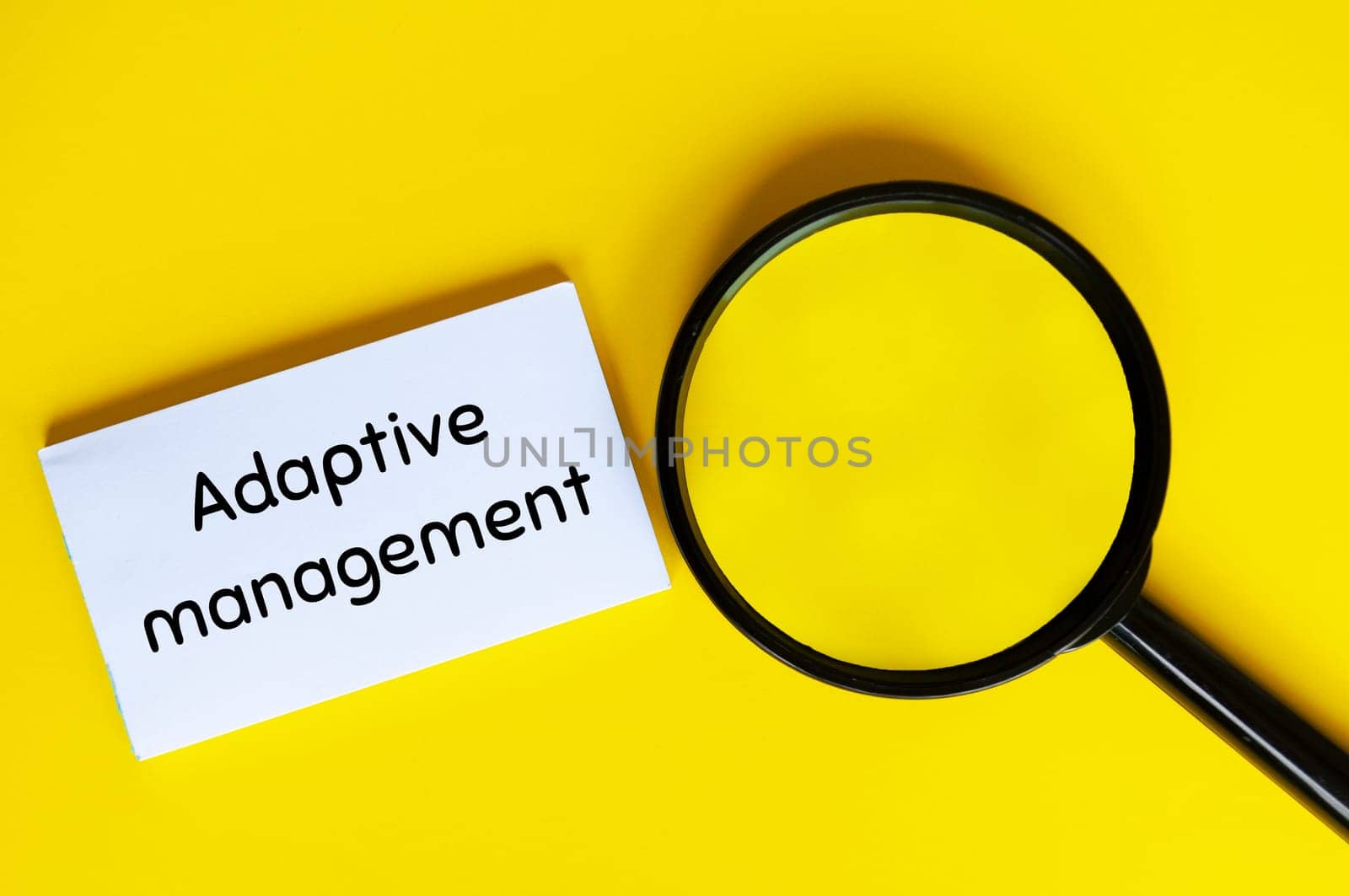 Adaptive management text on white notepad with magnifying glass. Business adaptivity concept.