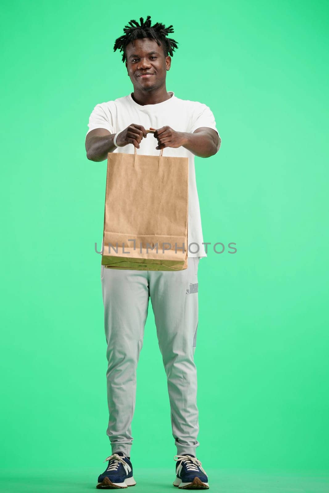 A man, full-length, on a green background, with bags.